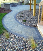 Grey-blue stone patio with wall, fire pit and curved walkway