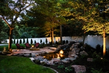 Backyard with rock water feature with water light and patio
