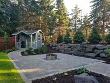 Square stone patio surrounded by wood chips and retaining wall