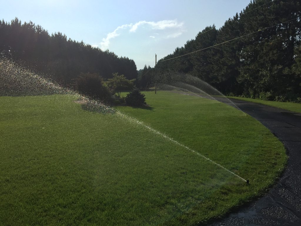 Paved road next to grass with sprinkler system